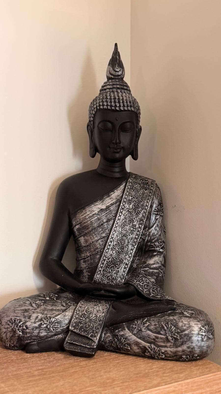 Statue de Bouddha en méditation, patinée argent, posée sur une console en bois