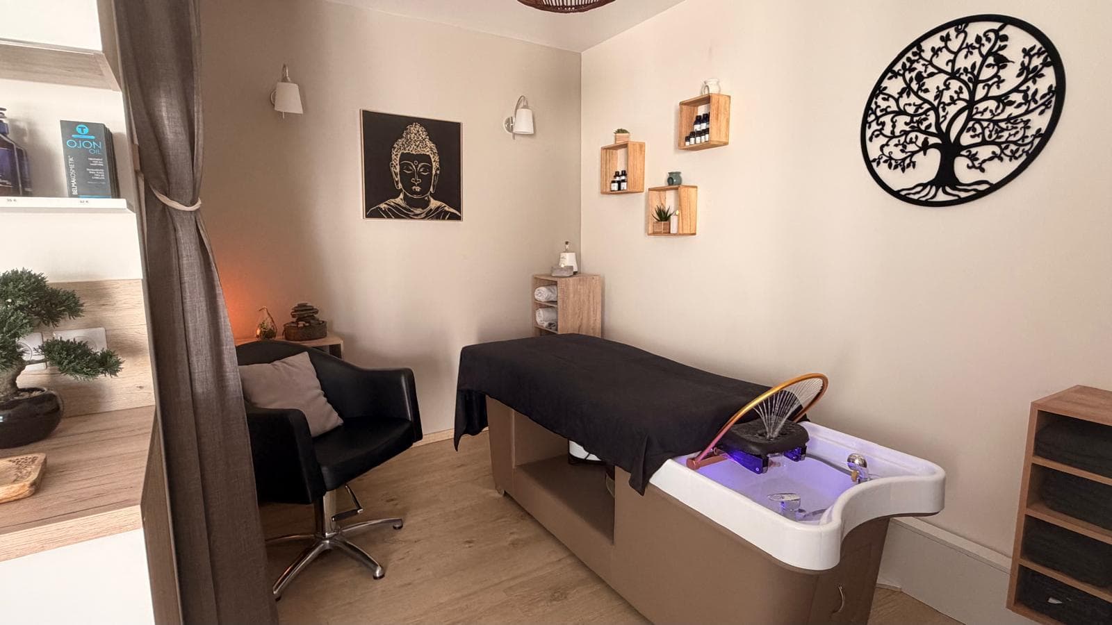 Salle de soin du salon : table de massage, bac Head Spa en chromothérapie, toile de Bouddha et arbre de vie